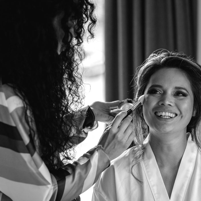 Anja Zander applying makeup to a laughing bride